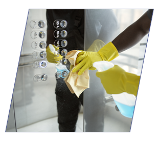 Un homme désinfectant les boutons d'un l'ascenseur